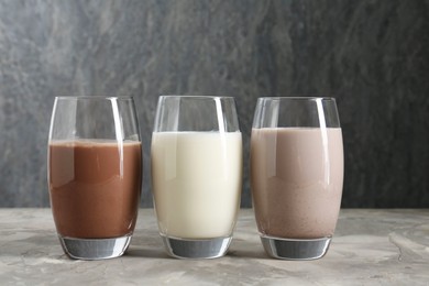 Photo of Delicious protein shakes in glasses on gray textured table