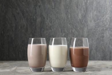 Photo of Delicious protein shakes in glasses on gray textured table, space for text