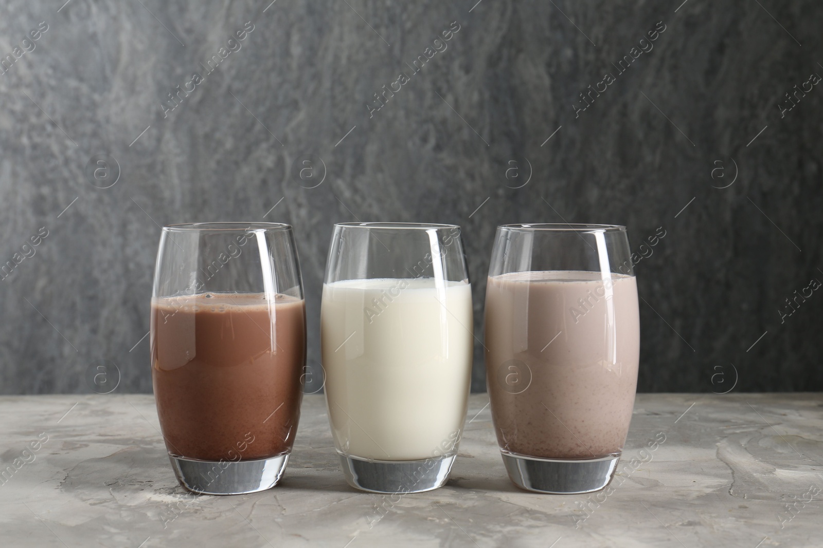 Photo of Delicious protein shakes in glasses on gray textured table