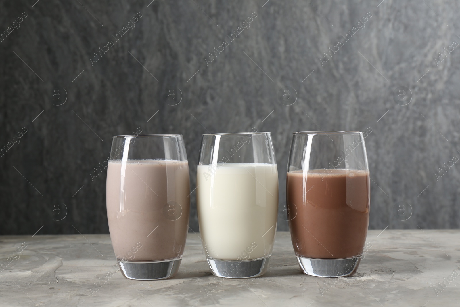 Photo of Delicious protein shakes in glasses on gray textured table