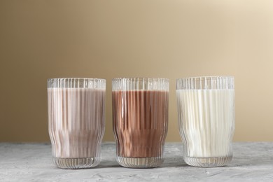 Photo of Delicious protein shakes in glasses on gray textured table against beige background