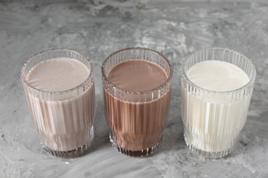 Photo of Delicious protein shakes in glasses on gray textured table, closeup