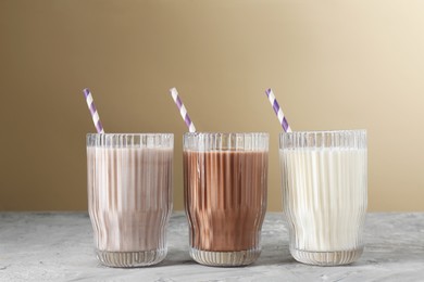 Photo of Delicious protein shakes in glasses on gray textured table against beige background