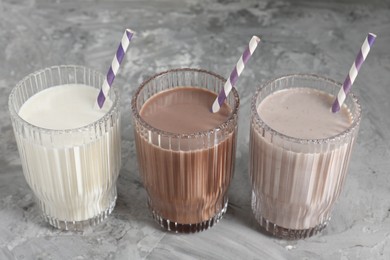 Photo of Delicious protein shakes in glasses on gray textured table, closeup