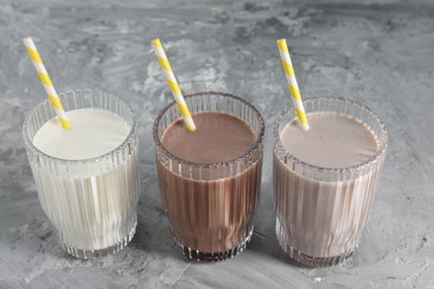 Photo of Delicious protein shakes in glasses on gray textured table, closeup