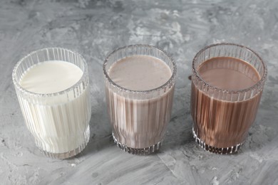 Photo of Delicious protein shakes in glasses on gray textured table, closeup