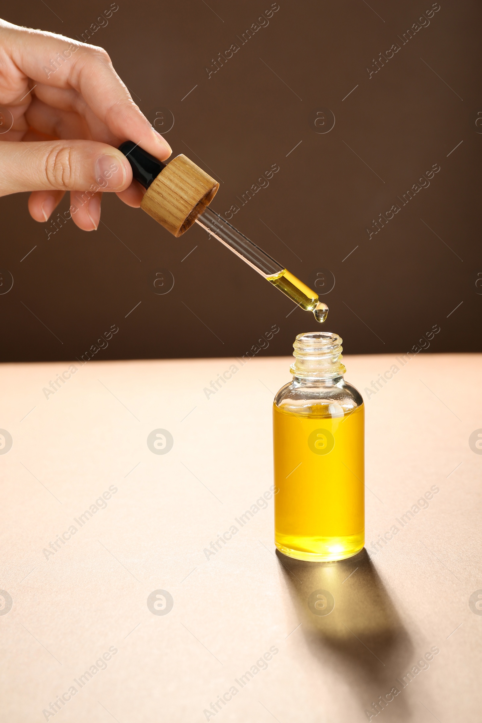 Photo of Woman dripping tincture from pipette into bottle on color background, closeup