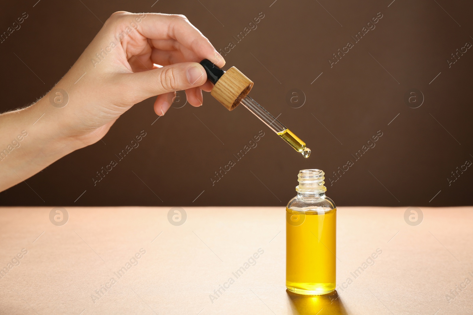 Photo of Woman dripping tincture from pipette into bottle on color background, closeup