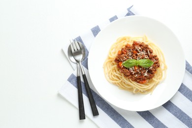 Photo of Delicious pasta bolognese and cutlery on white table, flat lay. Space for text