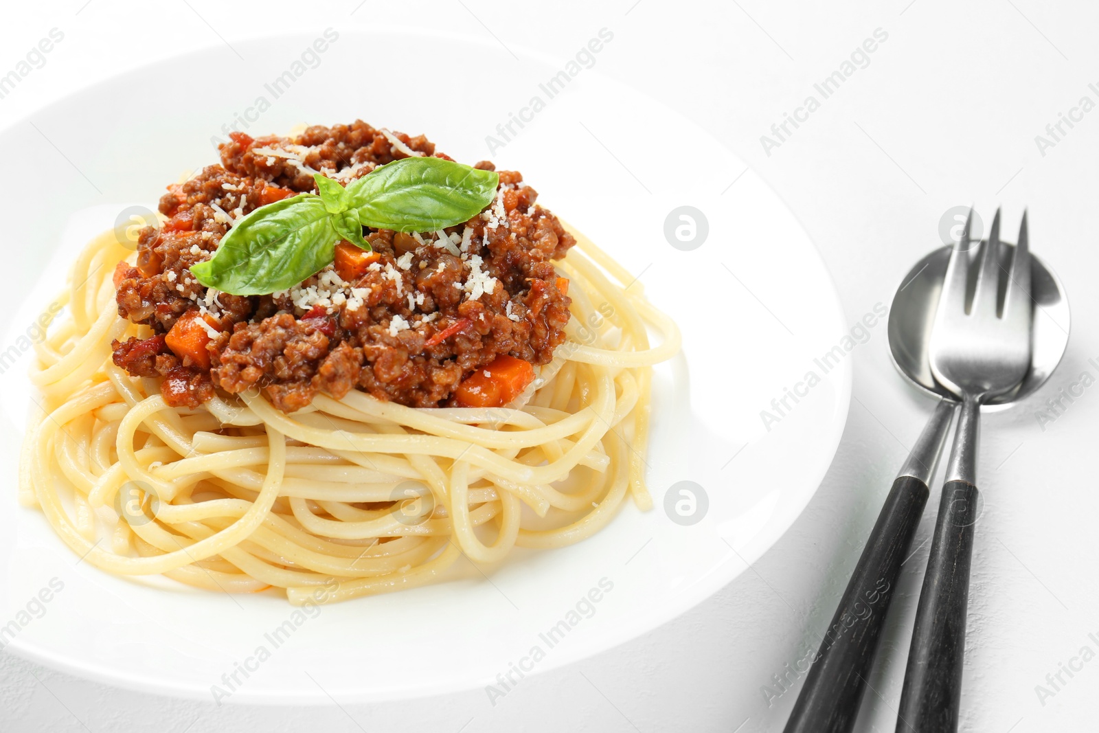 Photo of Delicious pasta bolognese and cutlery on white table, closeup