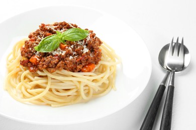 Photo of Delicious pasta bolognese and cutlery on white table, closeup