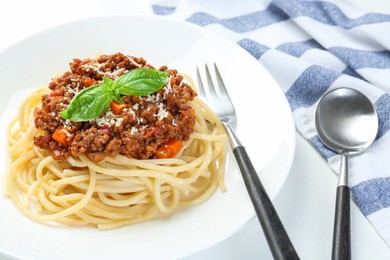 Photo of Delicious pasta bolognese and cutlery on white table, closeup