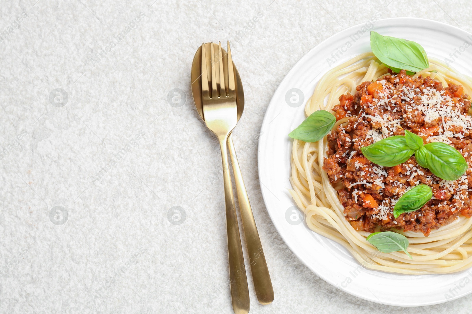 Photo of Delicious pasta bolognese and cutlery on white table, flat lay. Space for text