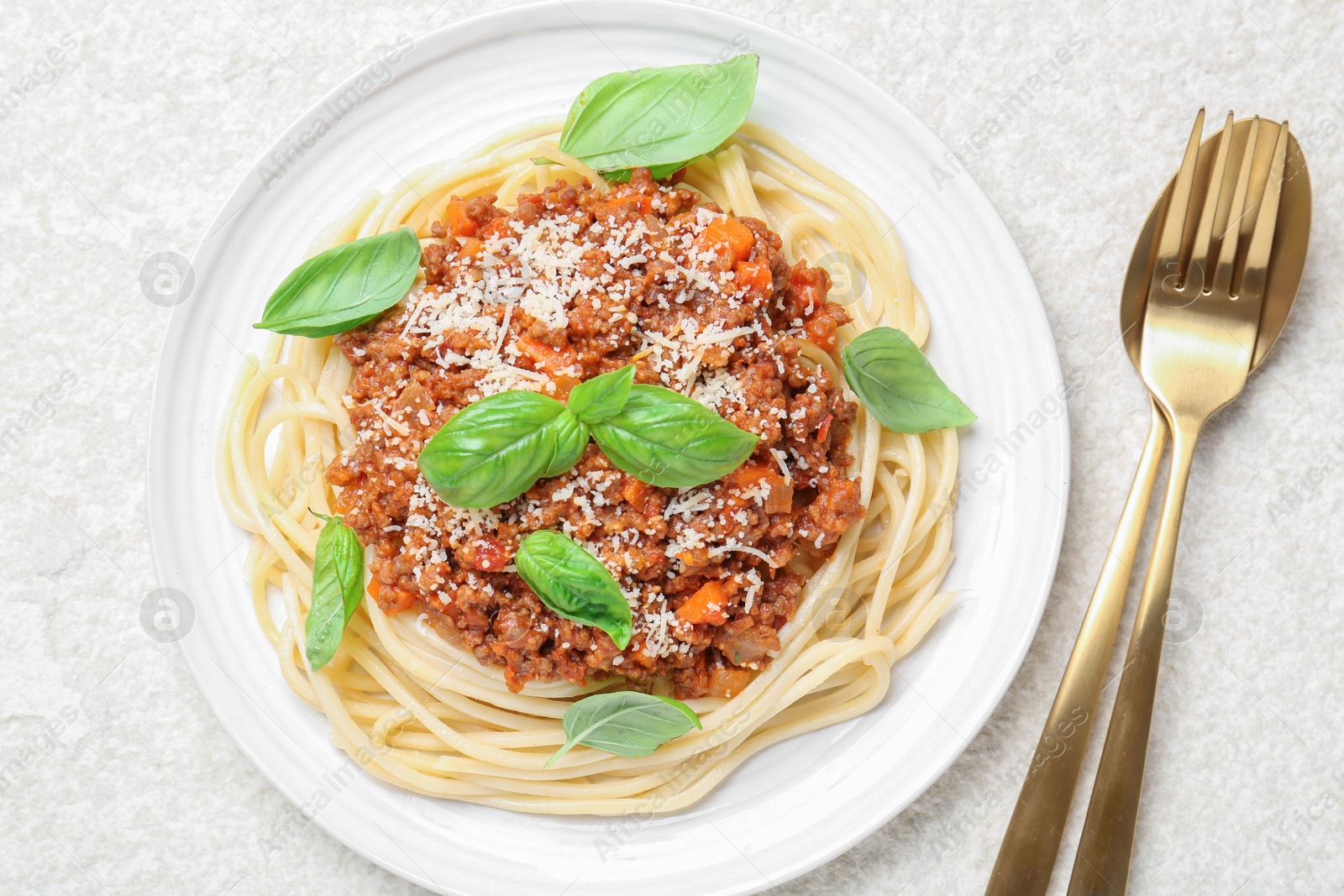 Photo of Delicious pasta bolognese and cutlery on white table, flat lay