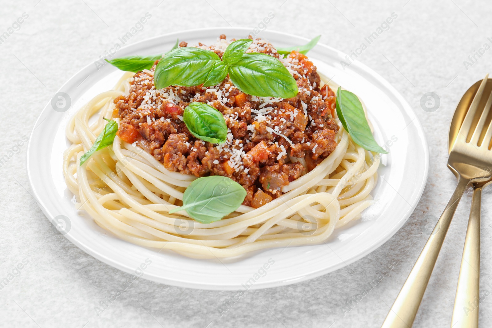 Photo of Delicious pasta bolognese and cutlery on white table, closeup