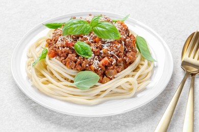 Photo of Delicious pasta bolognese and cutlery on white table, closeup