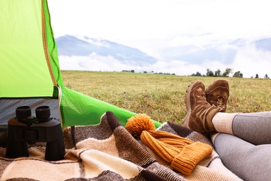 Photo of Woman wearing trekking shoes and lying in tent outdoors, closeup