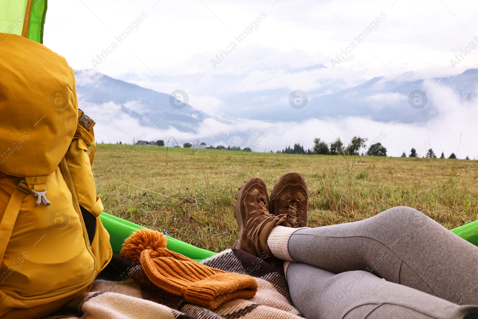 Photo of Woman wearing trekking shoes and lying in tent outdoors, closeup