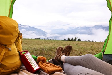 Photo of Woman wearing trekking shoes and lying in tent outdoors, closeup