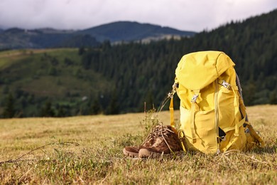 Backpack and trekking shoes on grass outdoors, space for text