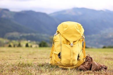 Backpack and trekking shoes on grass outdoors, space for text