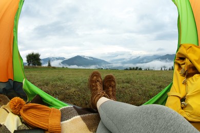 Woman wearing trekking shoes and lying in tent outdoors, closeup