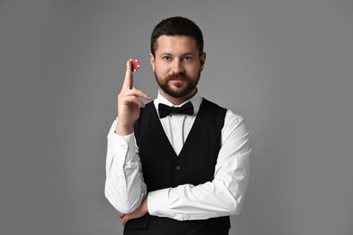 Croupier with casino chip on grey background