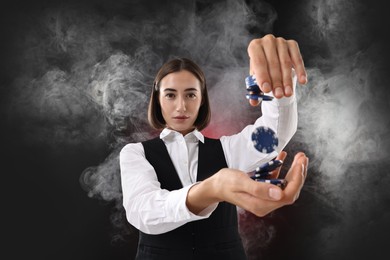 Croupier holding casino chips on dark red background with smoke