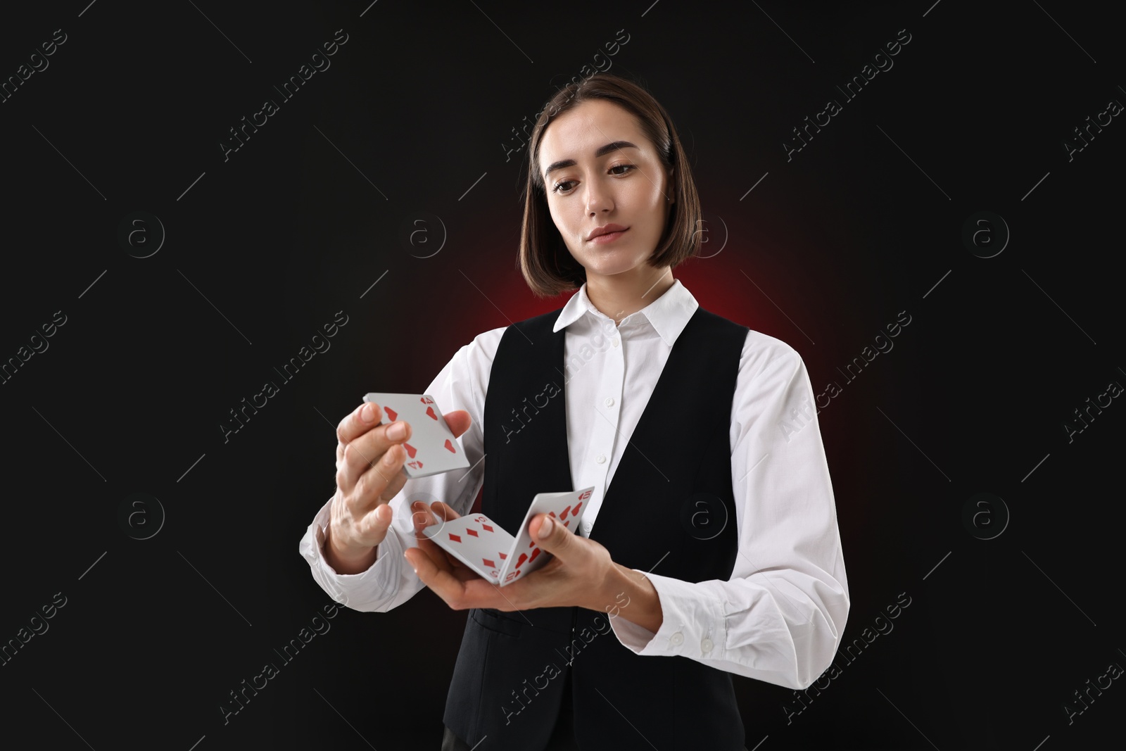 Photo of Professional croupier shuffling cards on dark red background