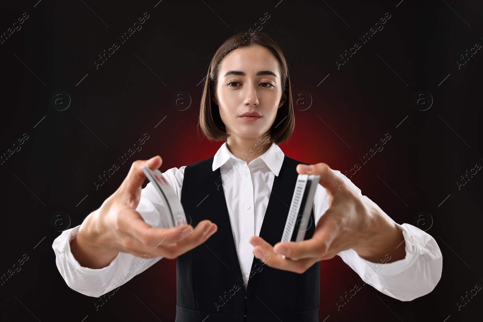 Photo of Professional croupier shuffling cards on dark red background