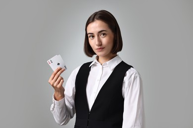 Professional croupier with playing cards on grey background