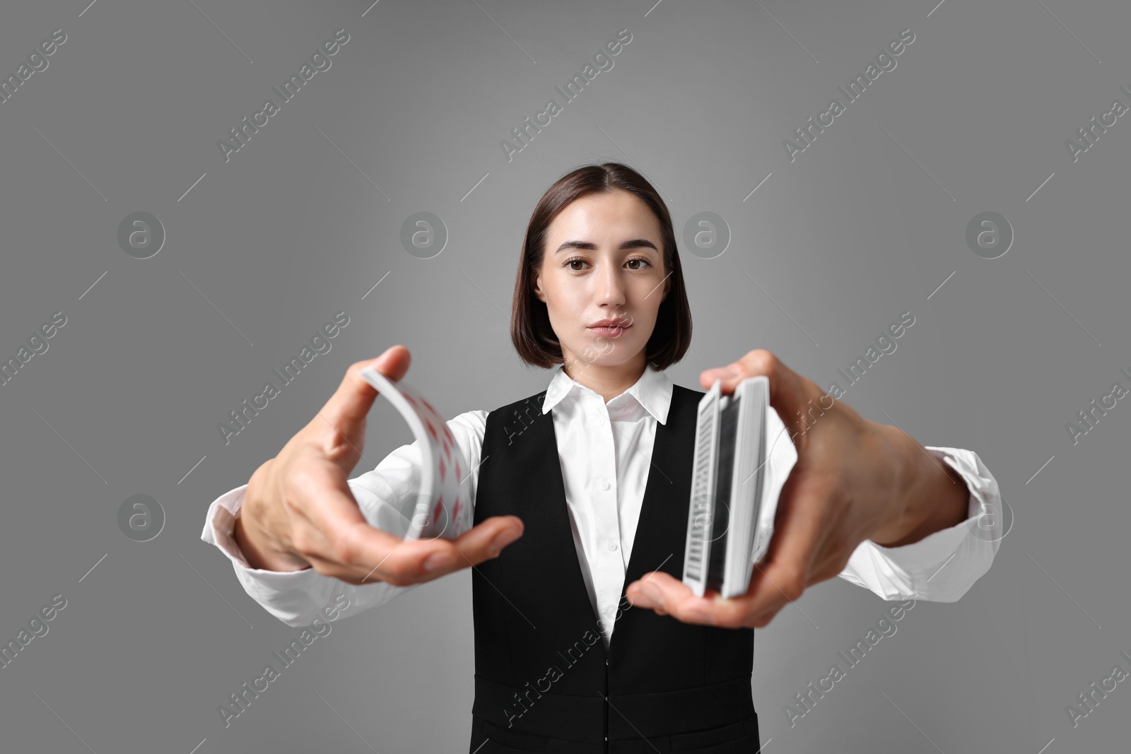 Photo of Professional croupier shuffling cards on grey background