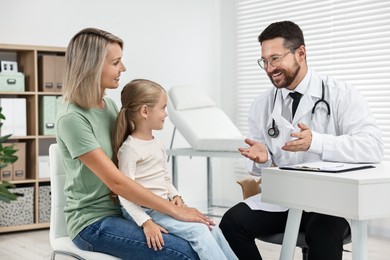 Doctor consulting little girl and her mother in hospital