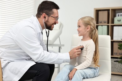 Photo of Doctor examining little girl with stethoscope in hospital