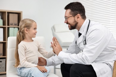 Little girl giving high five to doctor in hospital