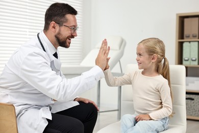 Photo of Little girl giving high five to doctor in hospital