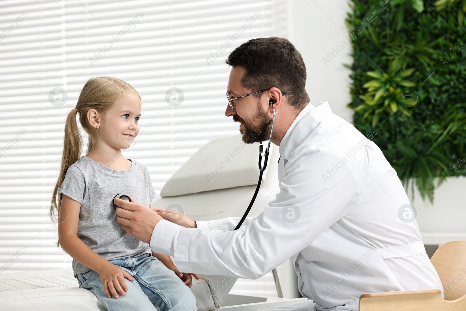 Photo of Doctor examining little girl with stethoscope in hospital