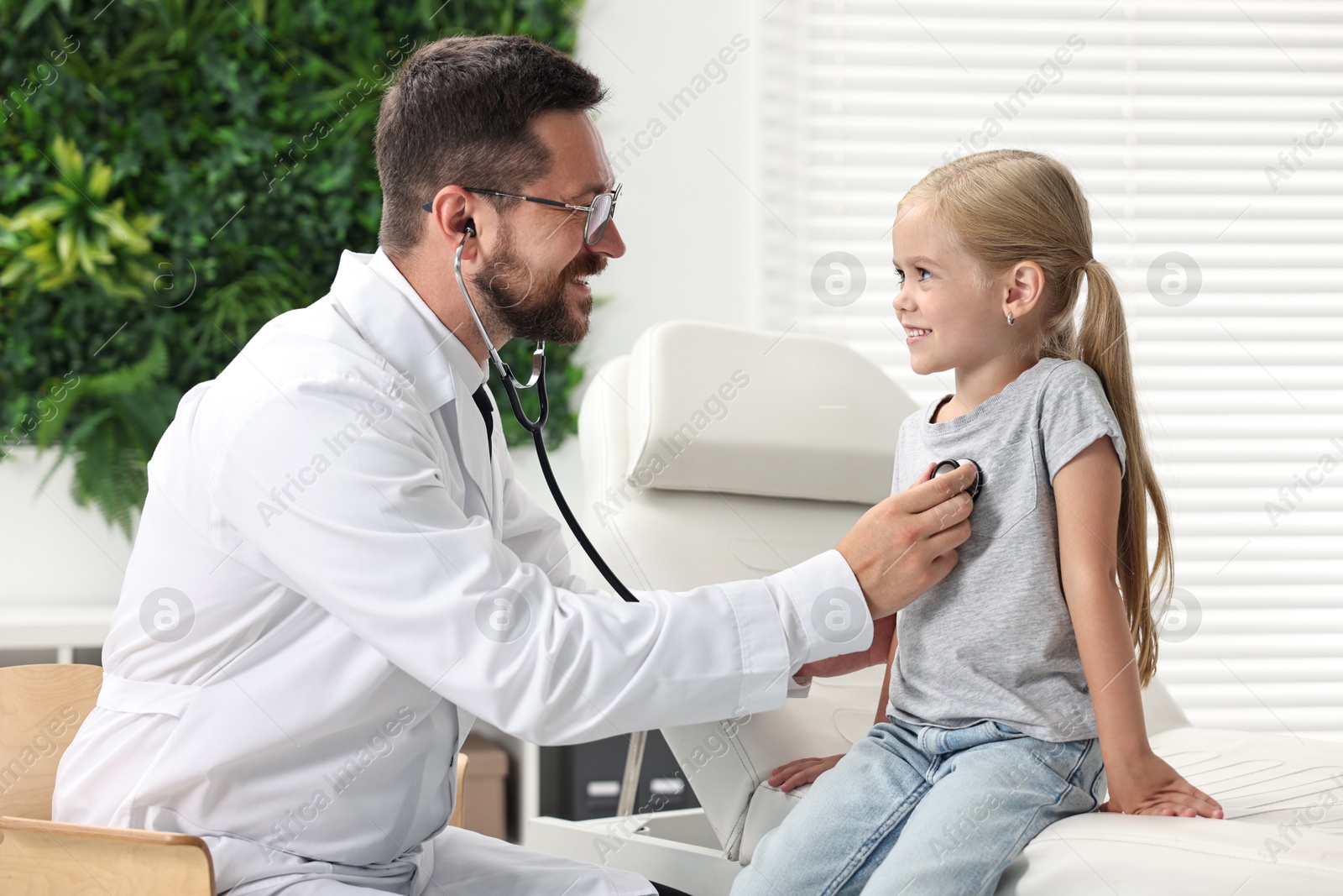 Photo of Doctor examining little girl with stethoscope in hospital