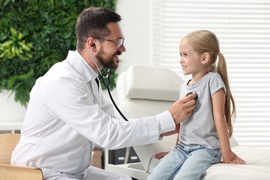 Doctor examining little girl with stethoscope in hospital