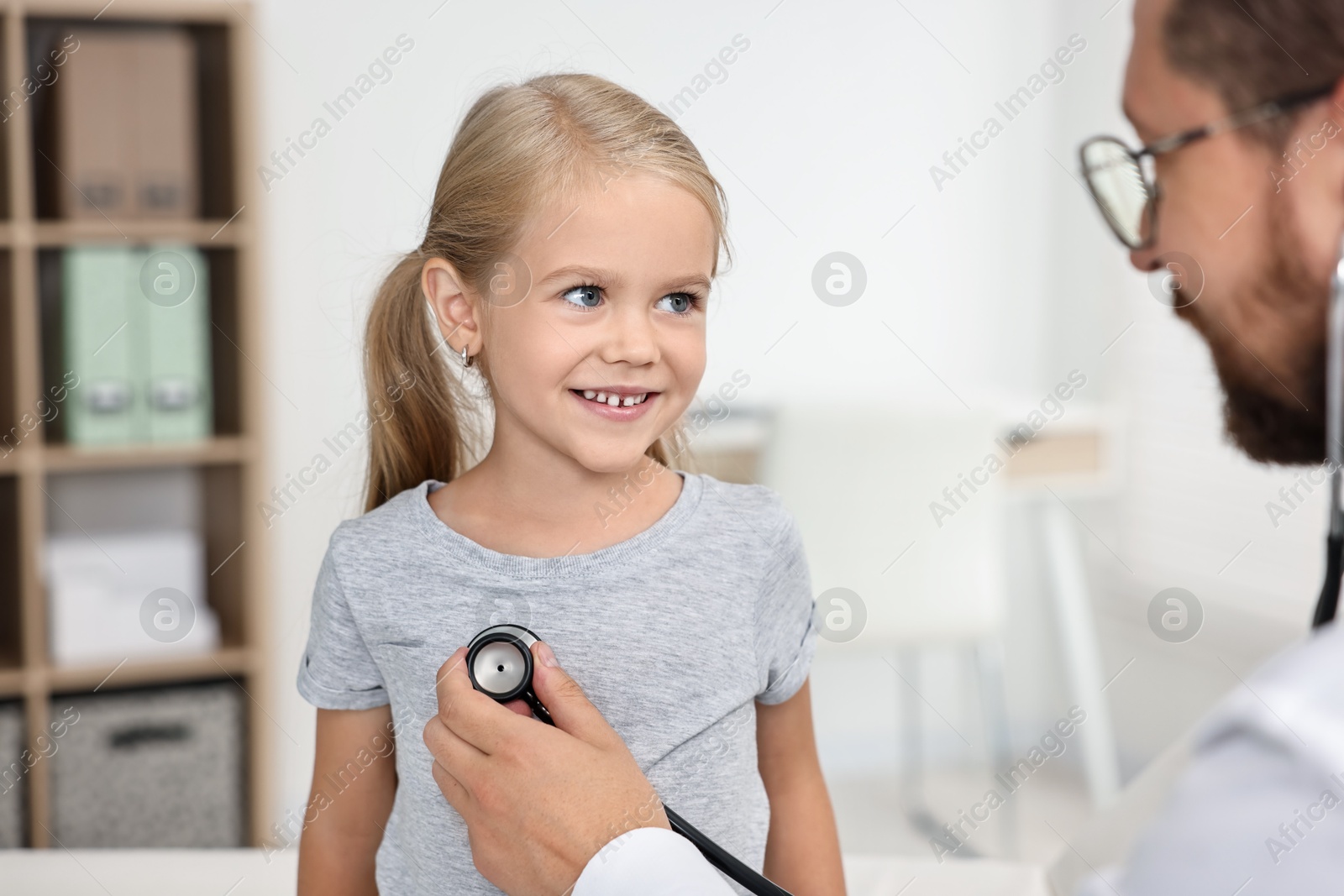 Photo of Doctor examining little girl with stethoscope in hospital, closeup