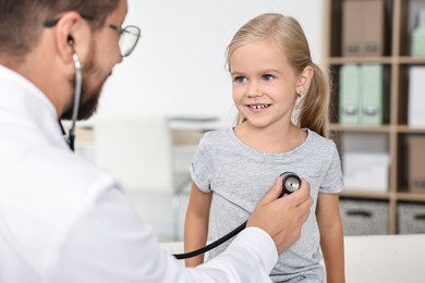 Photo of Doctor examining little girl with stethoscope in hospital, closeup