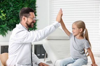 Doctor giving high five to little girl in hospital