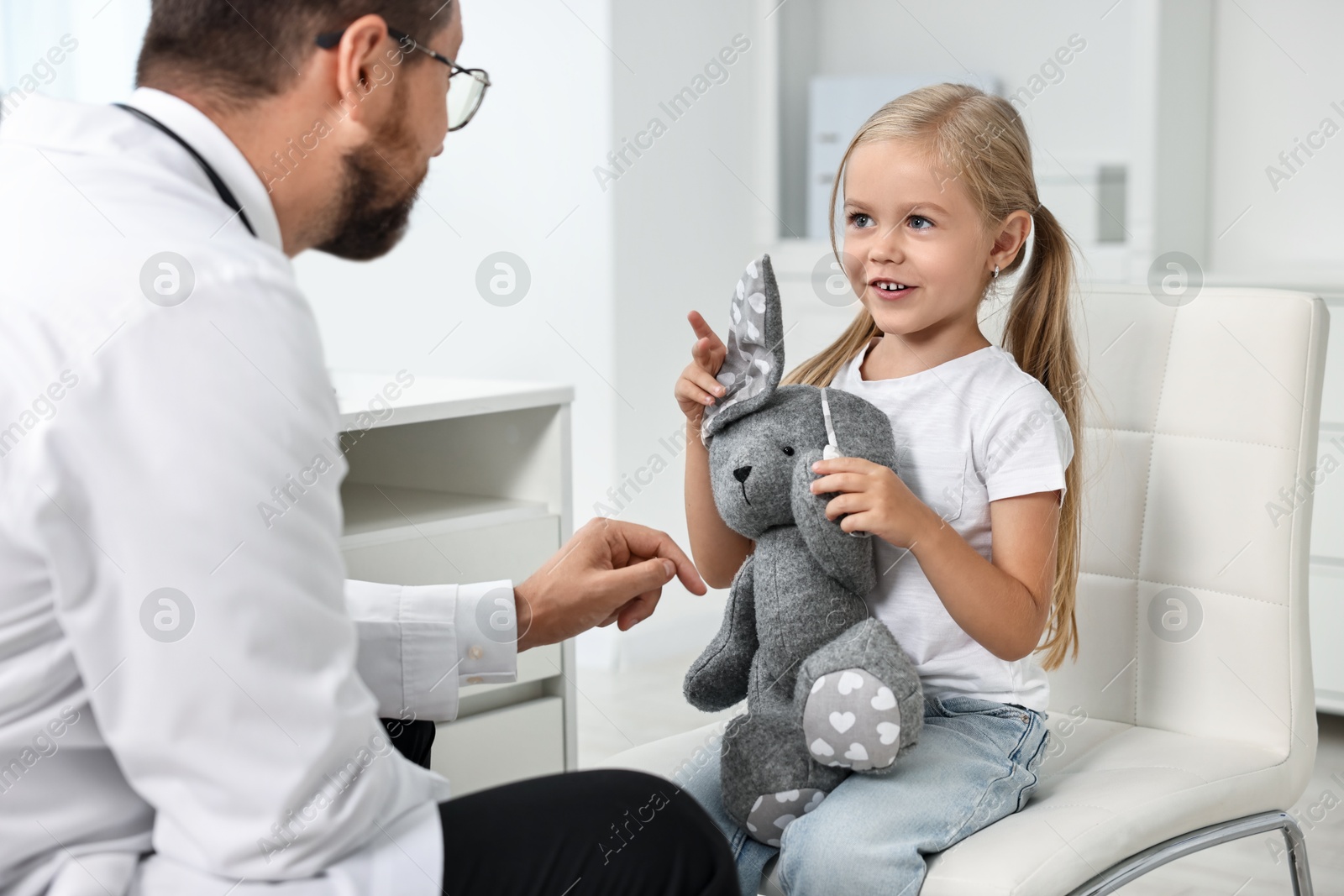 Photo of Little girl with toy having appointment with doctor in hospital