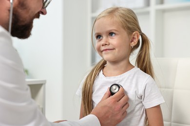 Photo of Doctor examining little girl with stethoscope in hospital, closeup