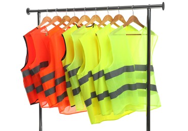 Photo of Different bright reflective vests on clothing rack isolated on white