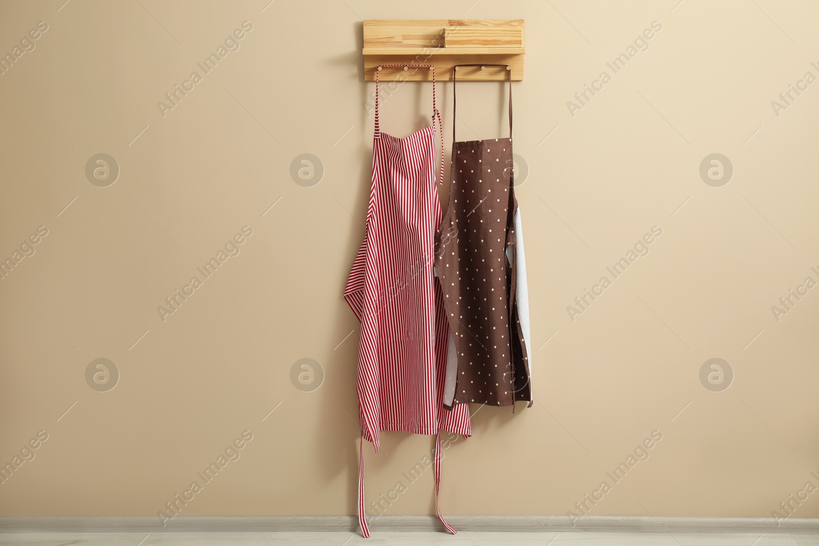 Photo of Two chef's aprons hanging on beige wall