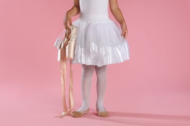 Little ballerina with pointe shoes on pink background, closeup