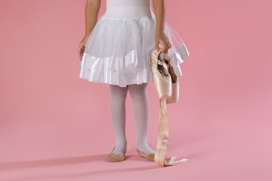 Little ballerina with pointe shoes on pink background, closeup