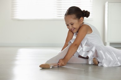 Photo of Little ballerina wearing pointe shoes indoors, space for text