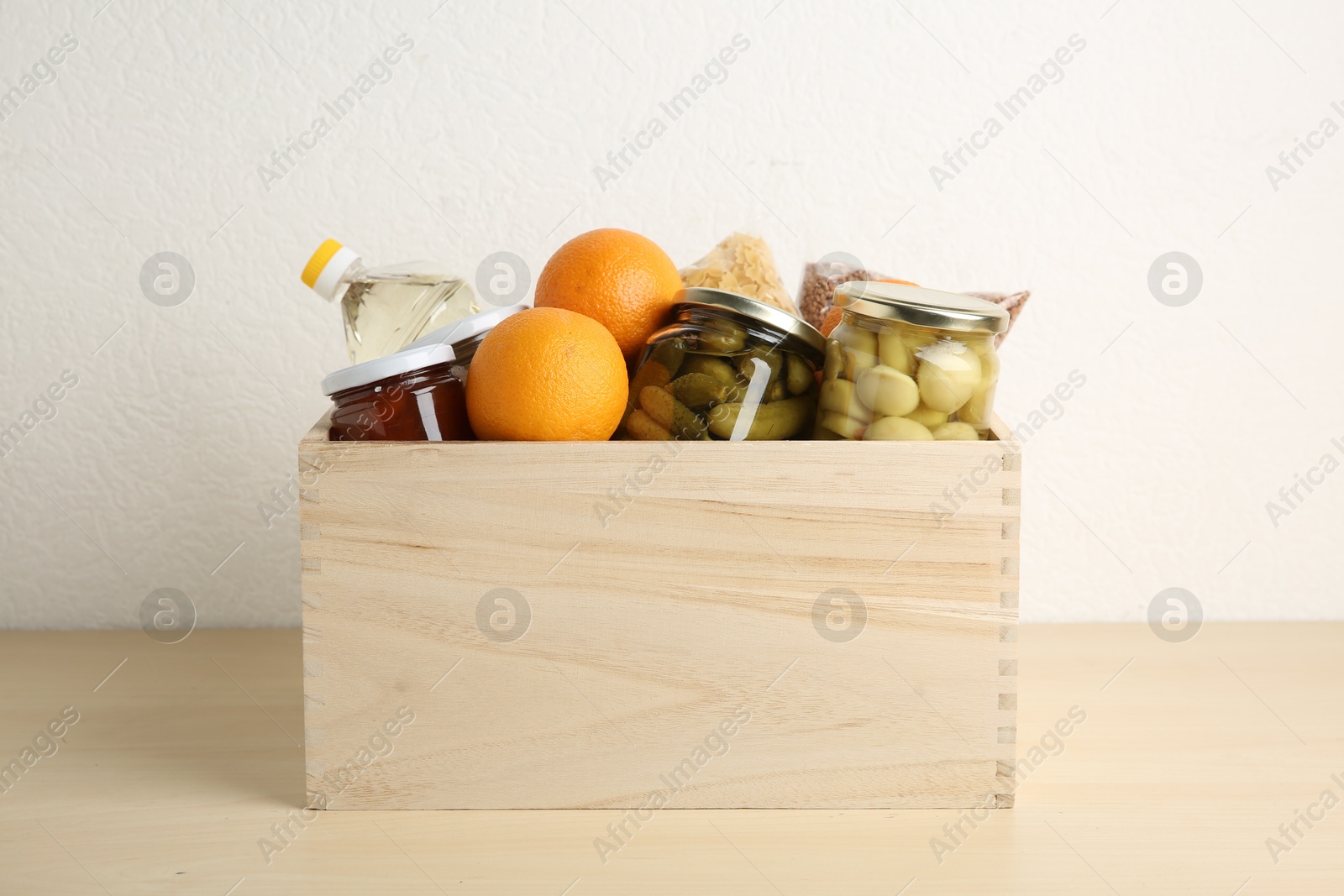 Photo of Different products in crate on wooden table. Food donation